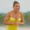 Fernanda Souza sorri em uma praia; ela usa vestido amarelo e está com cabelo preso num coque