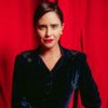 Fernanda Vasconcellos está com cabelo preto, usa um batom vermelho e blusa preta de manga longa