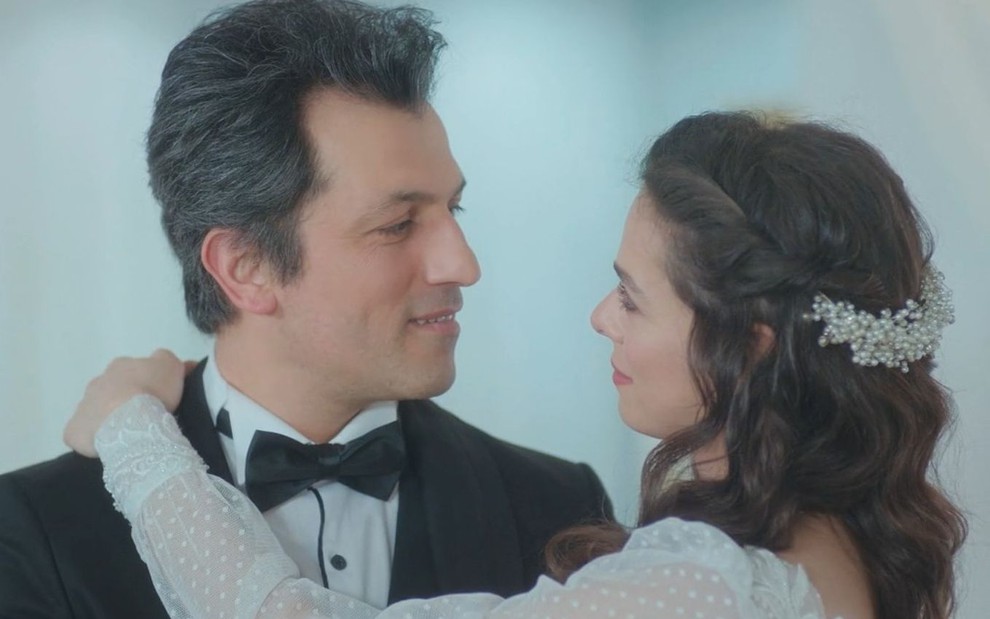Arif (Feyyaz Duman) e Bahar (Özge Özpirinçci) se olham; eles estão vestidos de noivos em cena da novela Força de Mulher