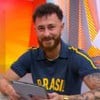 Fred Bruno está sentado, com um tablet nas mãos, e sorri no cenário do Globo Esporte