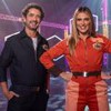 Felipe Andreoli e Rafa Brites na arena do Game dos 100, ambos usam macacões com a logo do programa; o dele é azul, e o dela é laranja