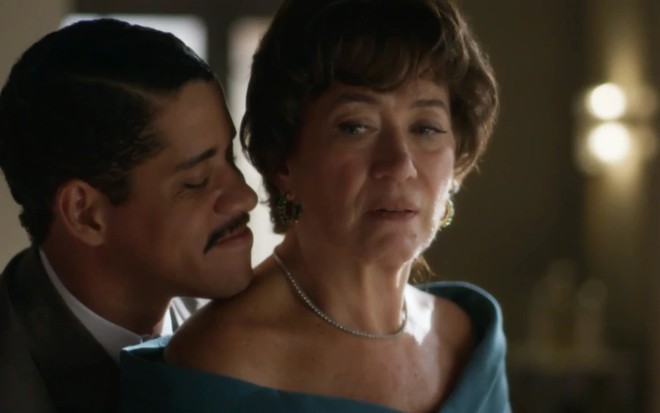 O ator Cauê Campos sorri perto do cangote da atriz Lilia Cabral, séria, em cena de Garota do Momento
