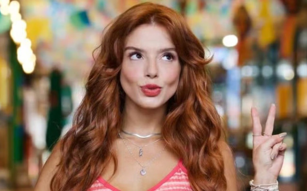 A atriz Giovanna Lancellotti fazendo biquinho e sinal de paz e amor com a mão, caracterizada como Kami em Dona de Mim