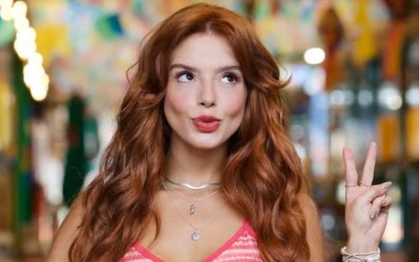 A atriz Giovanna Lancellotti fazendo biquinho e sinal de paz e amor com a mão, caracterizada como Kami em Dona de Mim