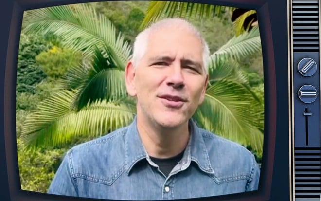 Carlos Gil está dentro de uma televisão estilizada e fala direto com a câmera