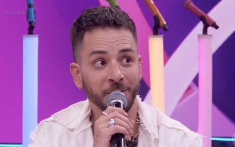 Junior Lima arregala os olhos enquanto fala ao microfone no palco do Caldeirão