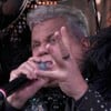 Milton Cunha usa terno preto com plumas e bexigas amarradas no palco do Domingão com Huck