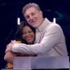 Luciano Huck abraça a participante Eliza no palco do Domingão; os dois sorriem emocionados, com expressão de carinho e apoio.