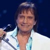 Roberto Carlos sorri forçadamente enquanto canta em seu especial de fim de ano