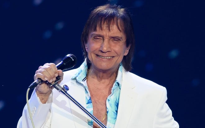 Roberto Carlos sorri forçadamente enquanto canta em seu especial de fim de ano