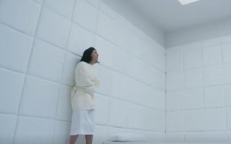 A atriz Carol Castro como Clarice presa em um quarto branco na novela Garota do Momento