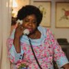 Duas mulheres conversam ao telefone fixo, cada uma em um ambiente florido e colorido, usando vestidos florais retrô