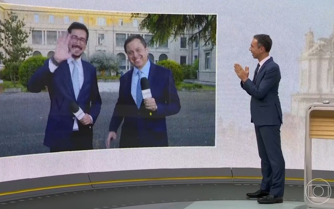 Nilson Klava e Gerson Camarotti acenam no telão do Jornal Hoje para César Tralli, que está no estúdio do noticiário