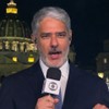 De terno e gravata, William Bonner segura microfone com a canopla da TV Globo na Praça São Pedro, no Vaticano