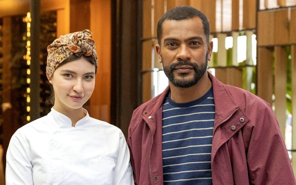 Alanis Guillen posa com Samuel de Assis no cenário do restaurante de Mania de Você, da Globo