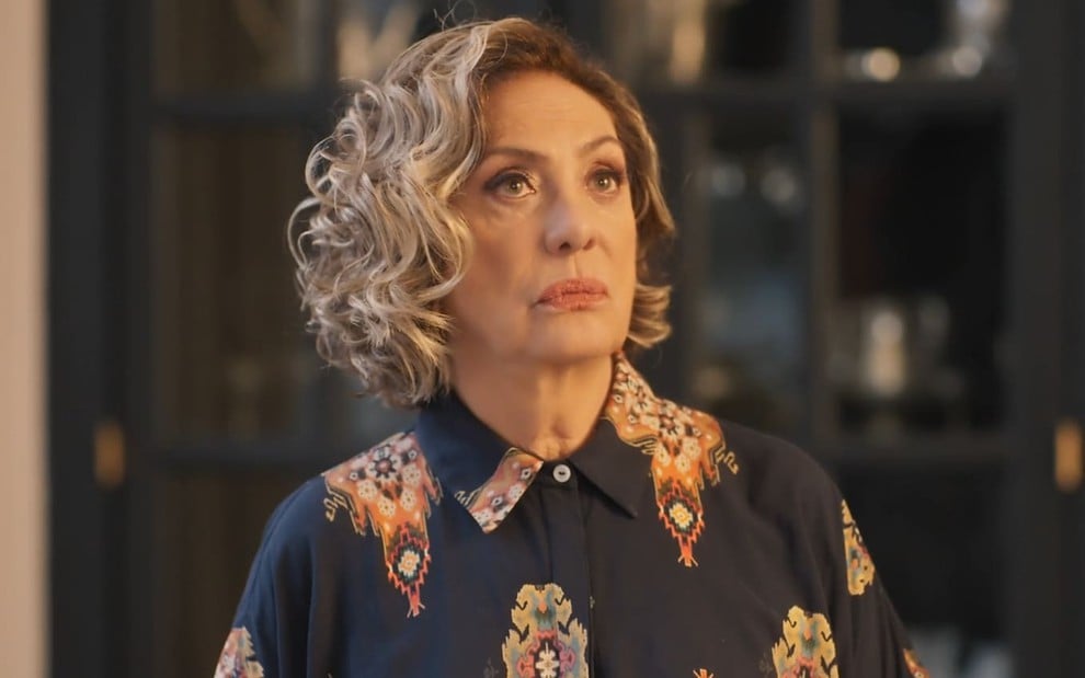 Eliane Giardini caracterizada como Berta; ela está séria em cena de Mania de Você