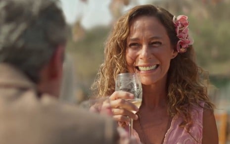 Andrea Beltrão sorri com uma taça de champanhe no último capítulo de No Rancho Fundo, da Globo