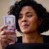 Bella Campos como Maria de Fátima segura maço de dólares no remake de Vale Tudo, da Globo