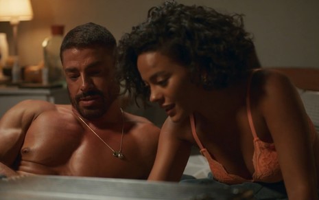 Cauã Reymond e Bella Campos estão juntos na cama, em roupas íntimas, em cena de Vale Tudo