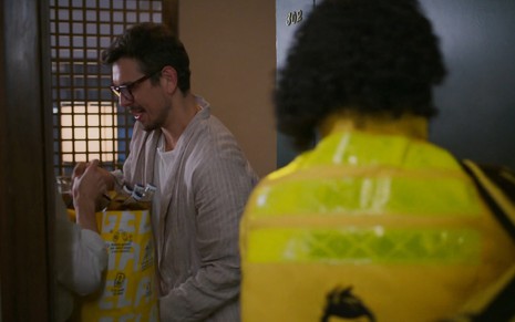 João Vicente de Castro segura uma sacola com bebidas em cena de Vale Tudo