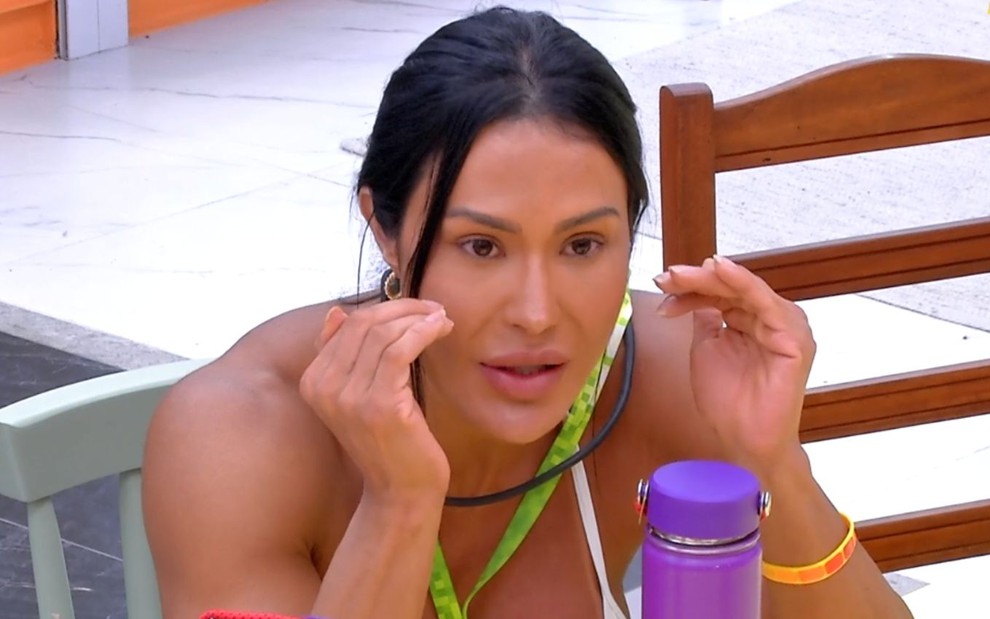 Gracyanne Barbosa está com os braços apoiados na mesa e estende as mãos no BBB 25