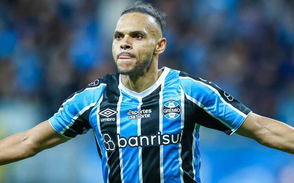 Braithwaite, do Grêmio, comemora gol e veste uniforme listrado em azul, branco e preto