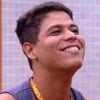 Guilherme Albuquerque sorridente no apê do líder no BBB 25; ele usa uma regata azul e está com colar laranja da liderança