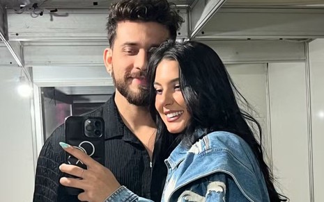 Gustavo Mioto e Ana Castela coladinhos, posando em frente a um espelho