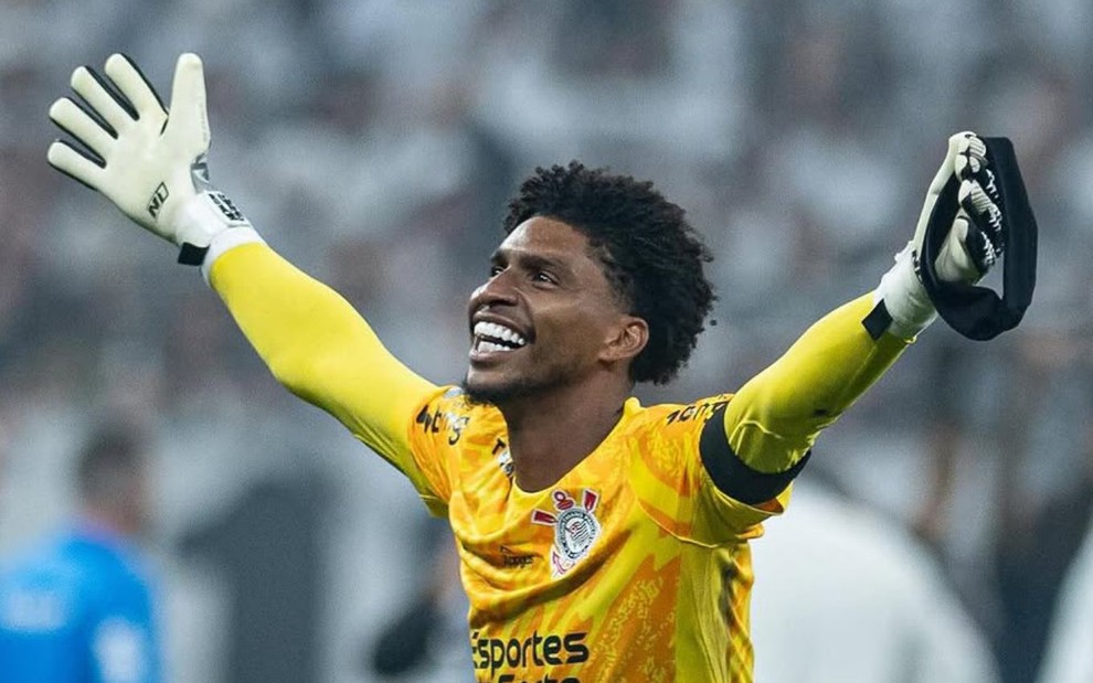 O goleiro Hugo Souza usa uniforme amarelo do Corinthians e está com os braços levantados