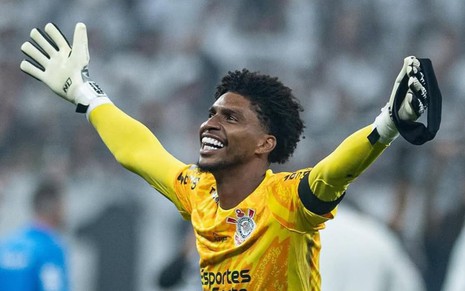O goleiro Hugo Souza usa uniforme amarelo do Corinthians e está com os braços levantados