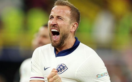 Kane, da Inglaterra, comemora gol pela seleção e veste uniforme branco com detalhes azuis