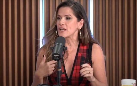 Ingrid Guimarães no cenário Quem Pode, Pod, com cabelo atrás da orelha e regata xadrez vermelha