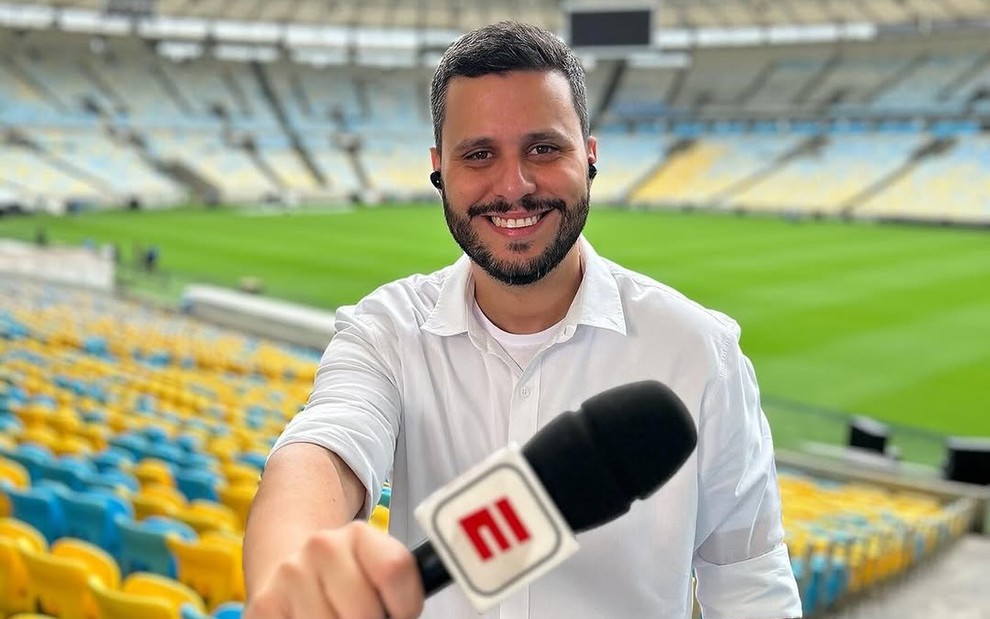 Fernando Campos segura microfone da ESPN em um estádio vazio de futebol