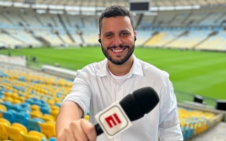 Fernando Campos segura microfone da ESPN em um estádio vazio de futebol
