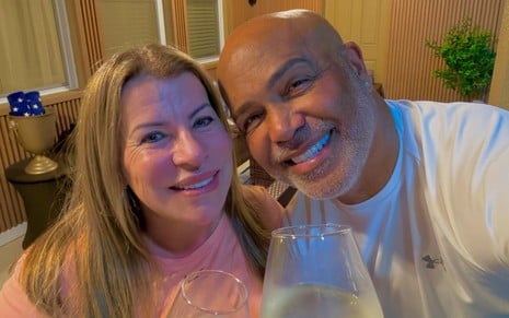 Geralda Helena e Rick Sollo posam para foto em uma mesa de jantar