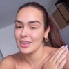 Montagem com Larissa Santos conversando com a câmera do celular e cacos de vidro em um chuveiro