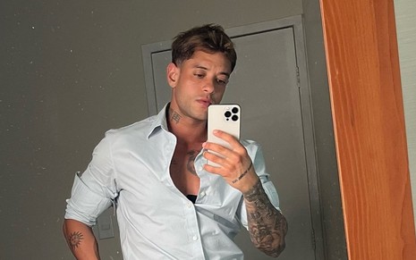 Homem com camisa social tira selfie no espelho