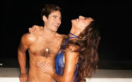 Sem camisa, Nicolas Prattes posa sorridente com Sabrina Sato, que gargalha enquanto abraça o ator