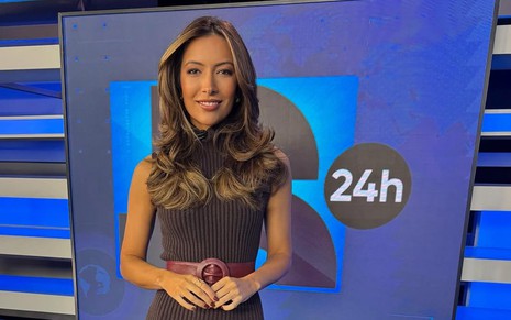 A jornalista Paloma Poeta com expressão neutra posa no cenário do JR 24H