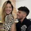 Virginia Fonseca está sentada no colo de Zé Felipe, os dois sorridentes, em uma área de churrasqueira