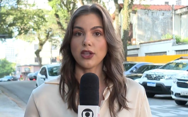 Isadora Marcos em link ao vivo do Bom Dia São Paulo; repórter está em cenário com árvores e carros de polícia