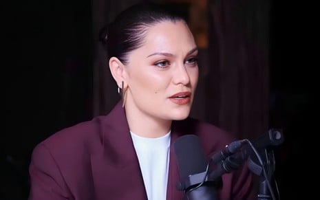 Jessie J no podcast The Diary of a CEO; ela usa blazer roxo em fundo escuro