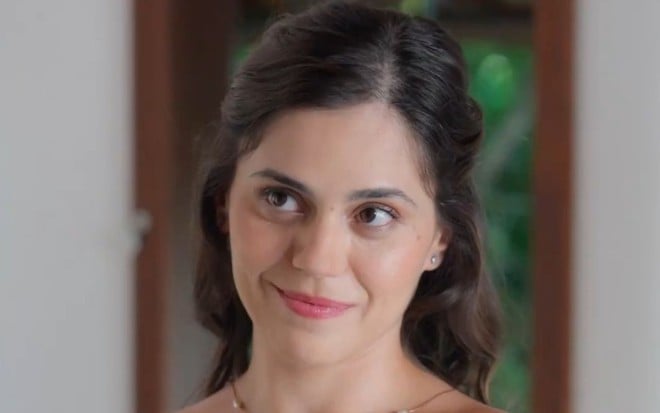Jessika Alves está com cabelo meio preso e sorri em cena de A Vida Secreta do Meu Marido Bilionário