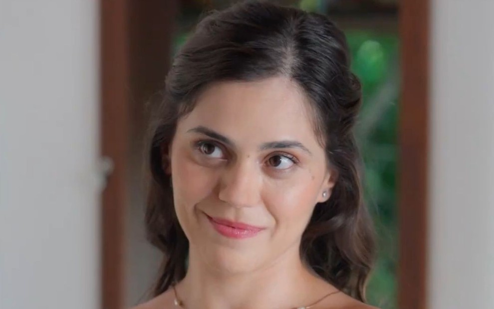 Jessika Alves está com cabelo meio preso e sorri em cena de A Vida Secreta do Meu Marido Bilionário