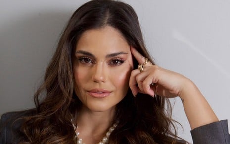 Jessika Alves na pré-estreia de Ben-Hu, posando em frente a painel com o nome da novela, usando vestido preto tomara-que-caia