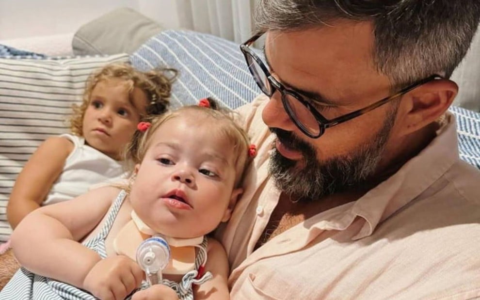 Juliano Cazarré segurando a filha, Maria Guilhermina, no colo quando ela era mais nova