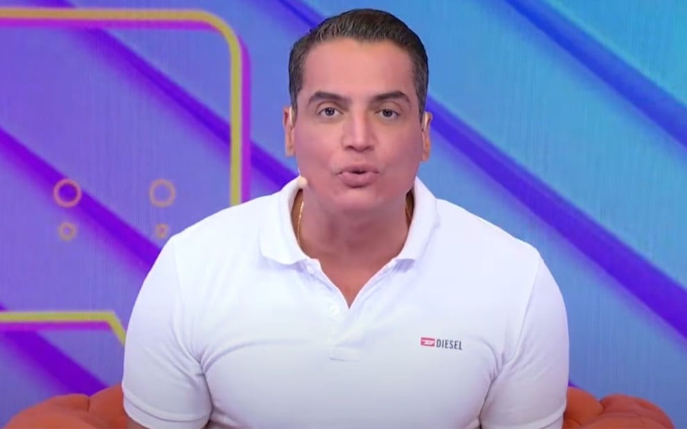 Leo Dias usa uma camisa polo branca e está com expressão séria no Fofocalizando