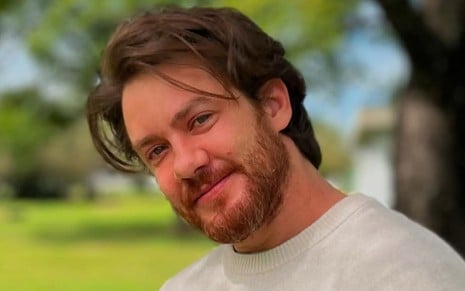 Leonardo Miggiorin está sorridente, em uma selfie tirada em um parque