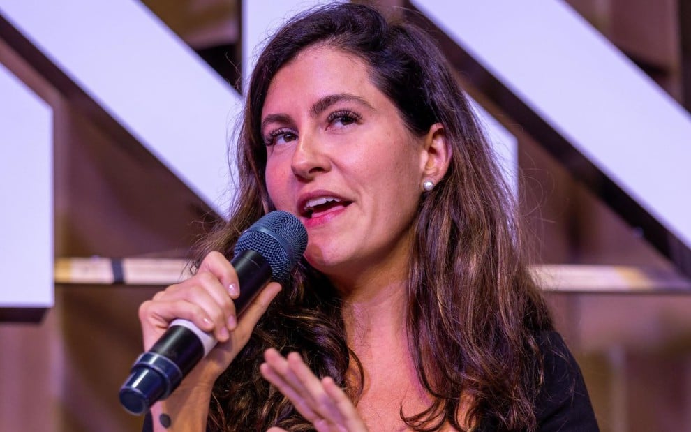 Leonora Bardini em palestra no evento Rio Innovation Week; ela fala em microfone