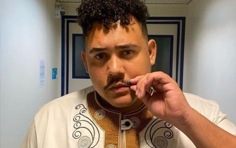 Lucas Henrique Ferreira, o Buda, em foto com cara séria, segurando o próprio bigode